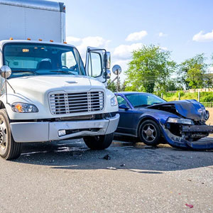 A truck and a damaged car parked on the side of the road after an accident - Sexton Weldon Law Firm