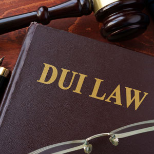 Brown leather book with "DUI LAW" embossed in gold letters, a gavel, a pen, and glasses are nearby | Sexton Weldon Law Firm